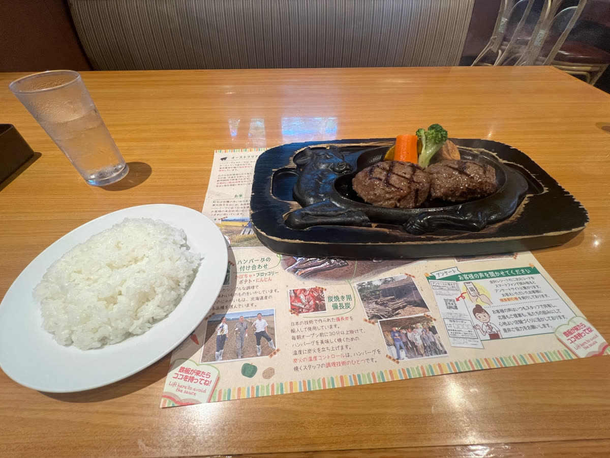 牛の形の鉄板にのったハンバーグと、ライス・お冷やが並ぶテーブル