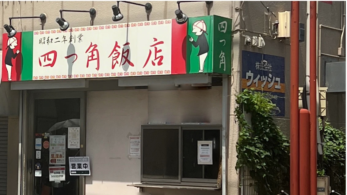 「昭和二年創業 四つ角飯店」の看板を掲げた店舗外観